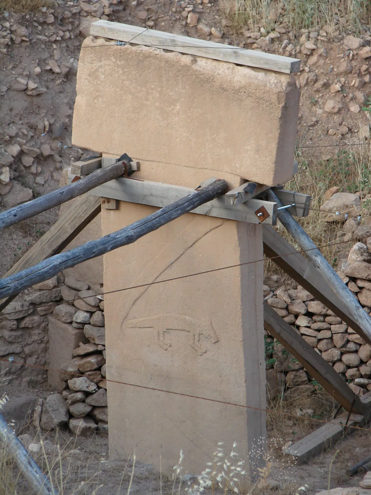 A T-shaped pillar with a carved arm and fox.