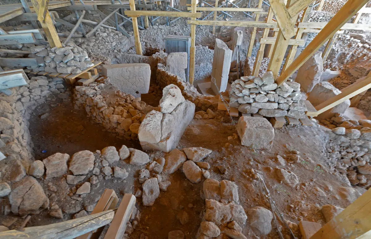 Stone walls and pillars in the Göbekli Tepe excavation beneath a protective roof.