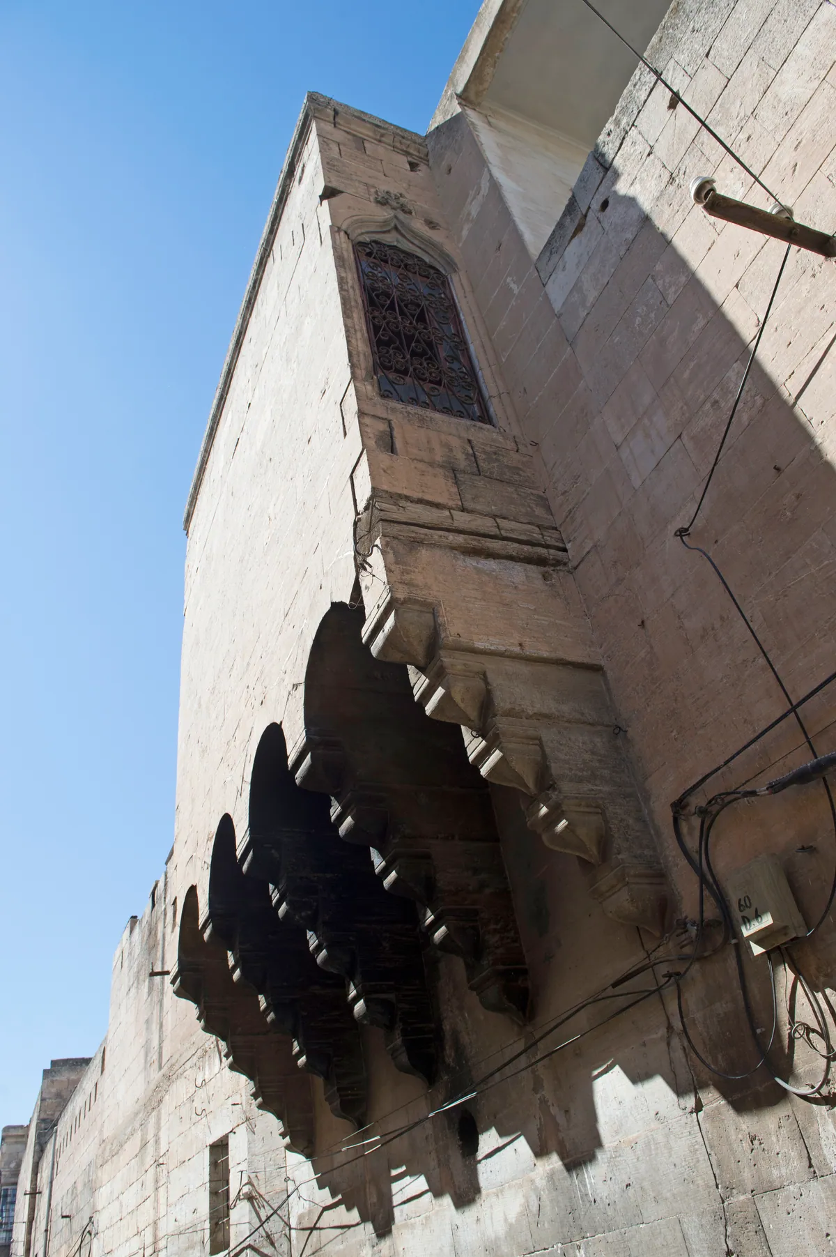 An upward view of carved stone brackets projecting beneath dark windows.